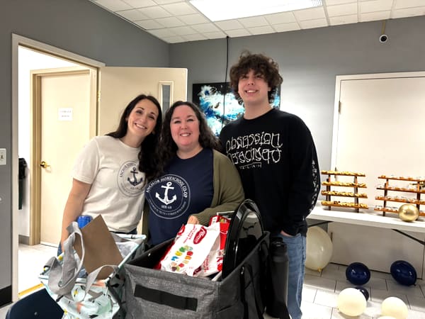 Anchor Homeschool Co-op leaders and a student wearing Anchor gear while setting up for an event